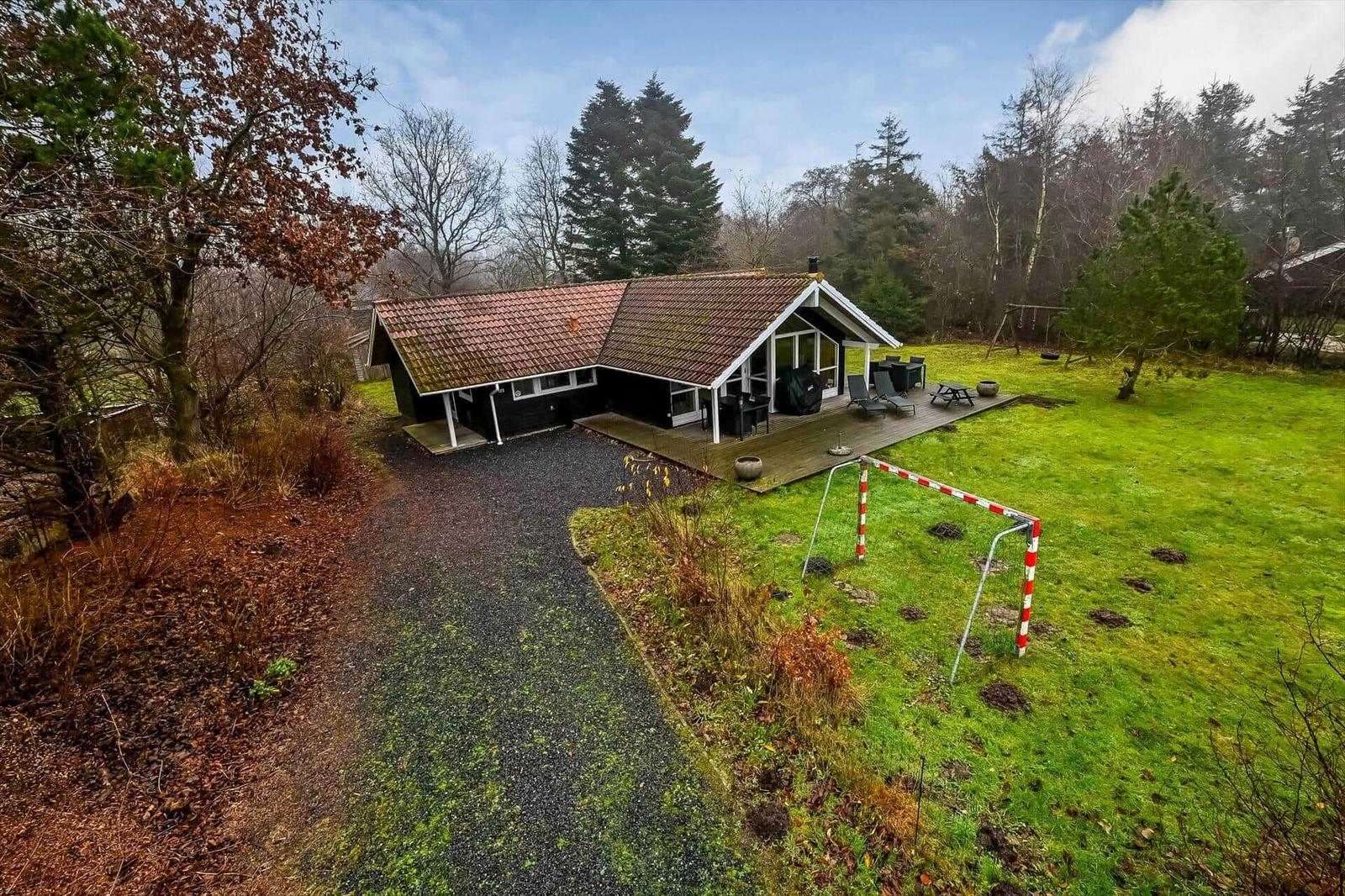 Haus mit Terrasse, Garten und Fußballtor. Umgeben von Bäumen und Grasfläche.
