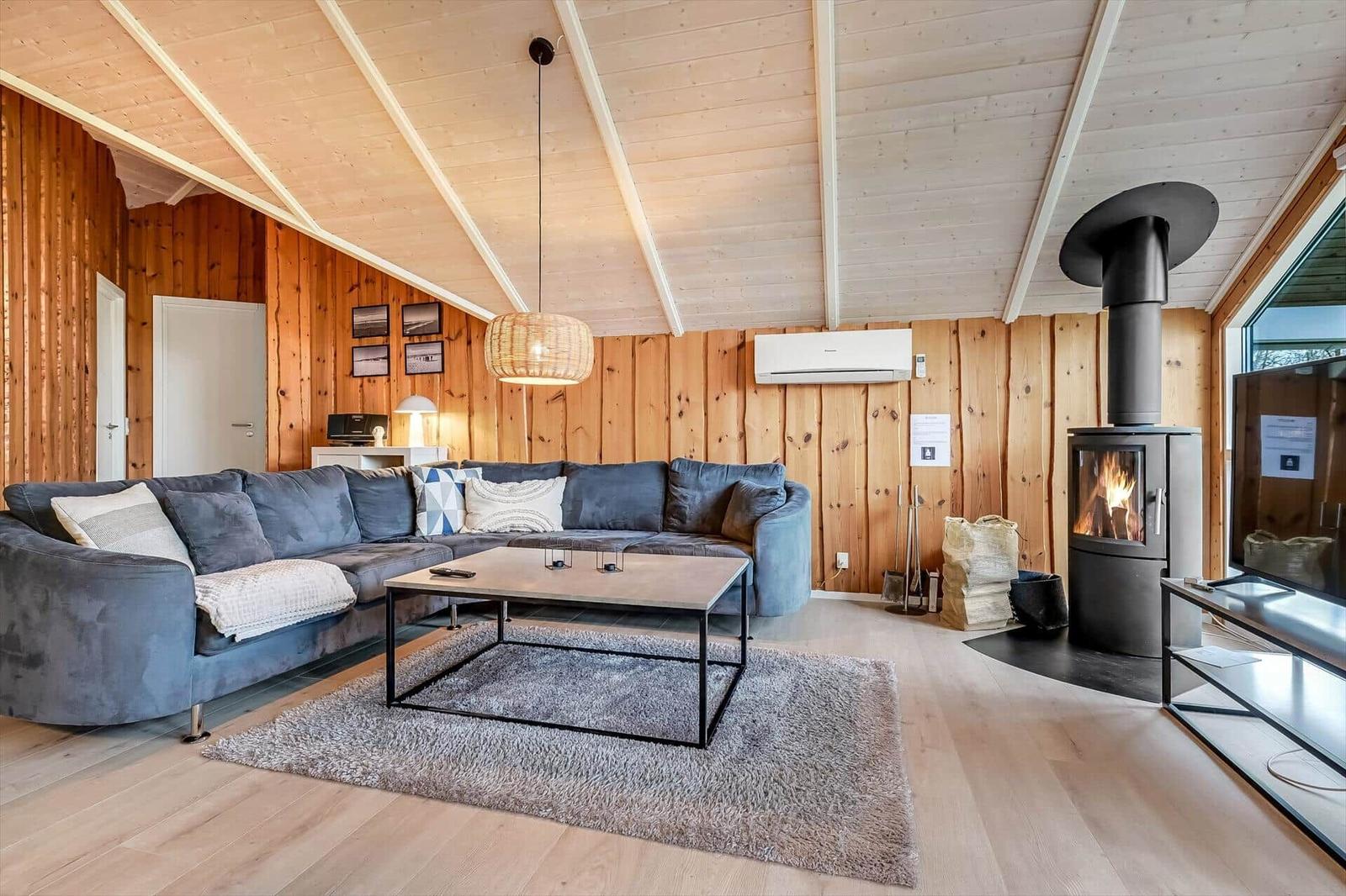 Wohnzimmer mit Sofa, Kamin und Holzwandverkleidung.