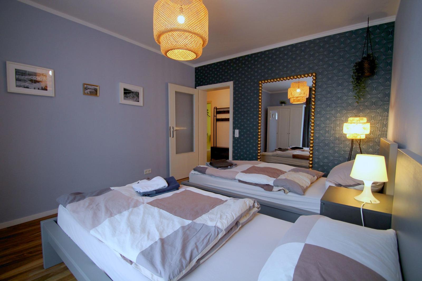 Zwei Betten mit Bettwäsche, Wand mit Spiegel und Deckenbeleuchtung.
