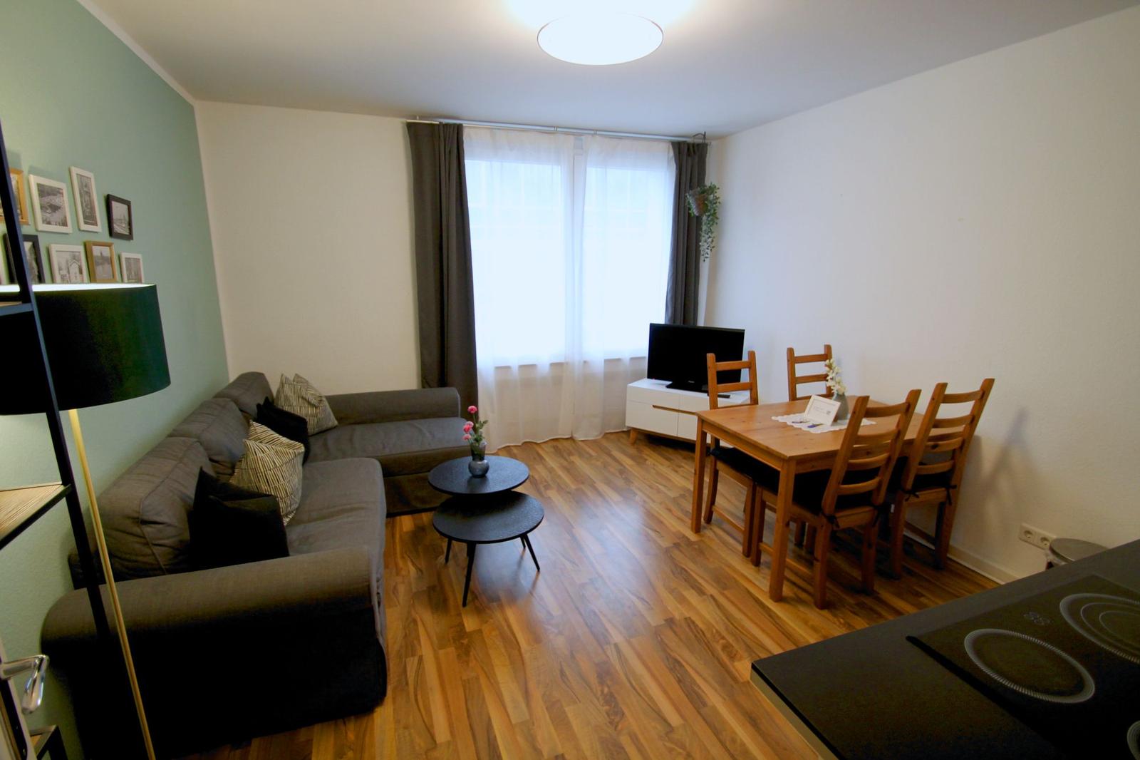 Wohn- und Essbereich mit Sofa, Esstisch und Holzboden.