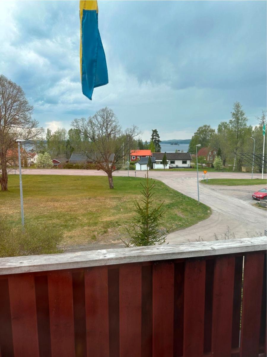 Blick von Balkon mit schwedischer Flagge auf Dorf und See.