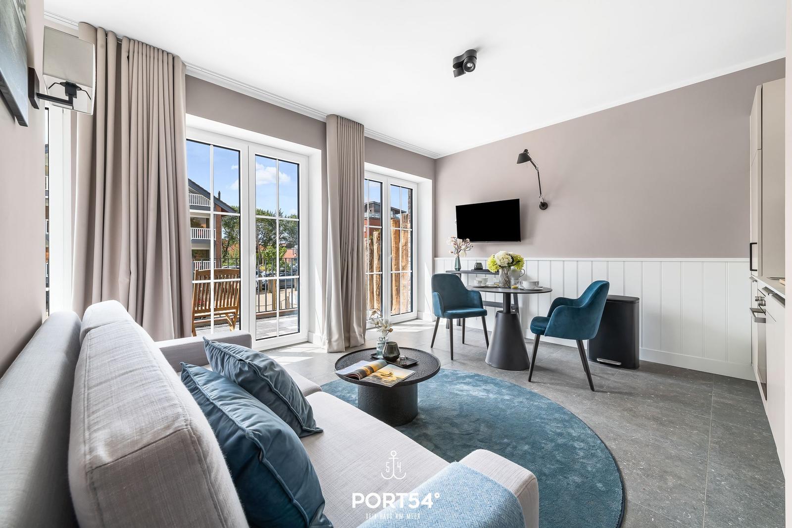 Wohnbereich mit Sofa, Esstisch und Blick auf Balkon