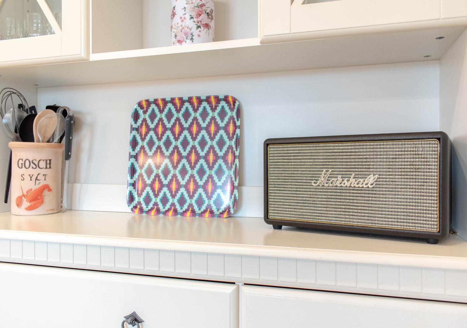 Küchenarbeitsfläche mit Lautsprecher, Servierplatte und Küchenutensilien.