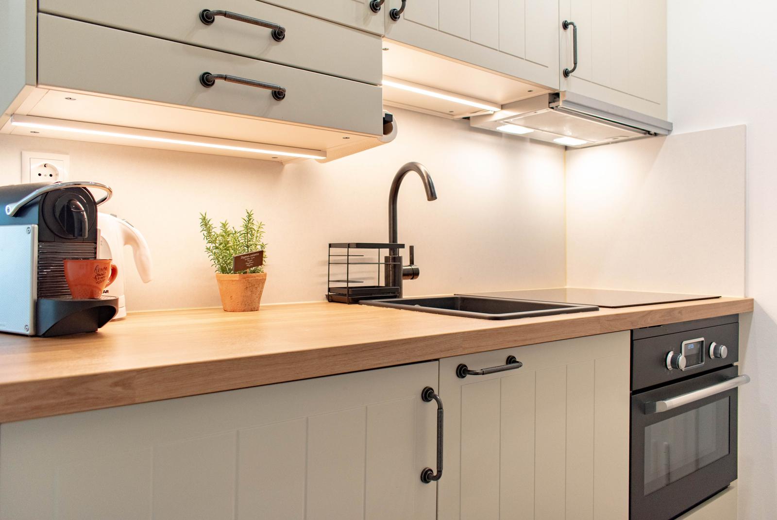 Küche mit Arbeitsplatte, Spüle, Kaffeemaschine und Ofen.