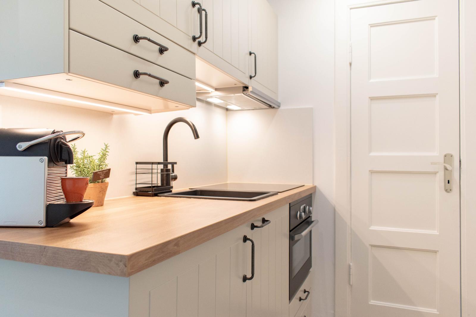 Küche mit Holz-Arbeitsplatte, Edelstahl-Spüle und integriertem Ofen.