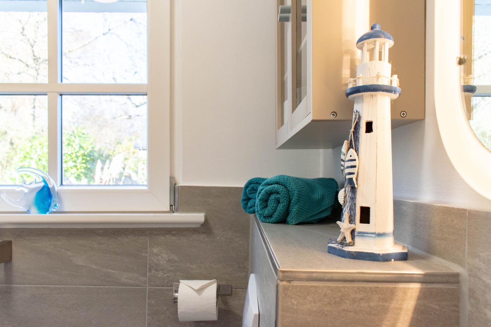 Badezimmer mit Fenster, Handtuch und Leuchtturm-Dekoration