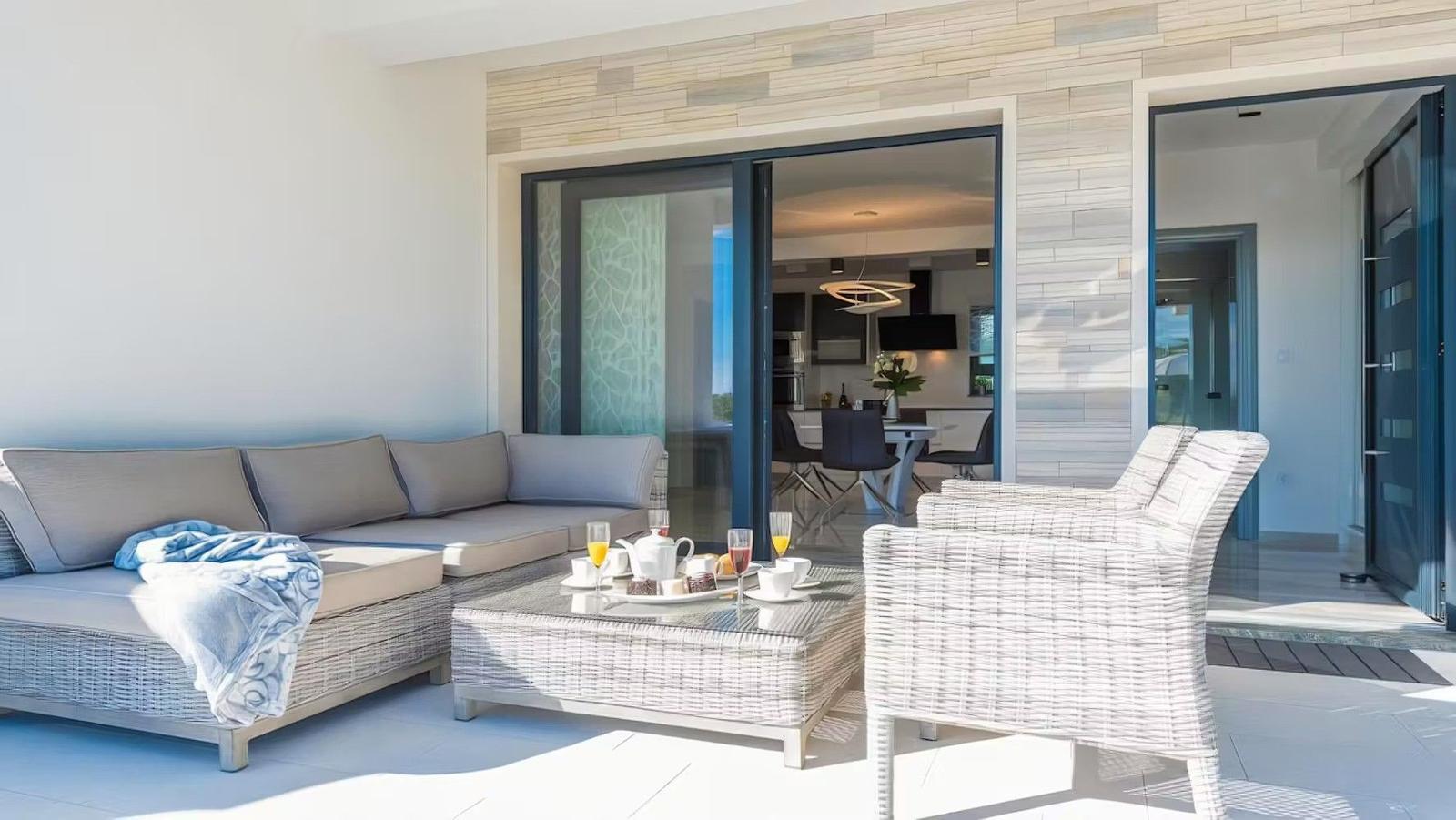 Terrace with sofa, table and chairs. Entrance to the interior of the house.