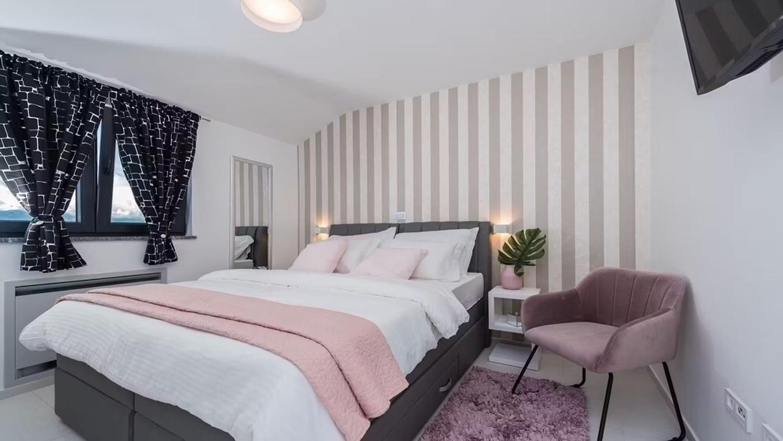 Bedroom with bed, chair, and window with curtains.