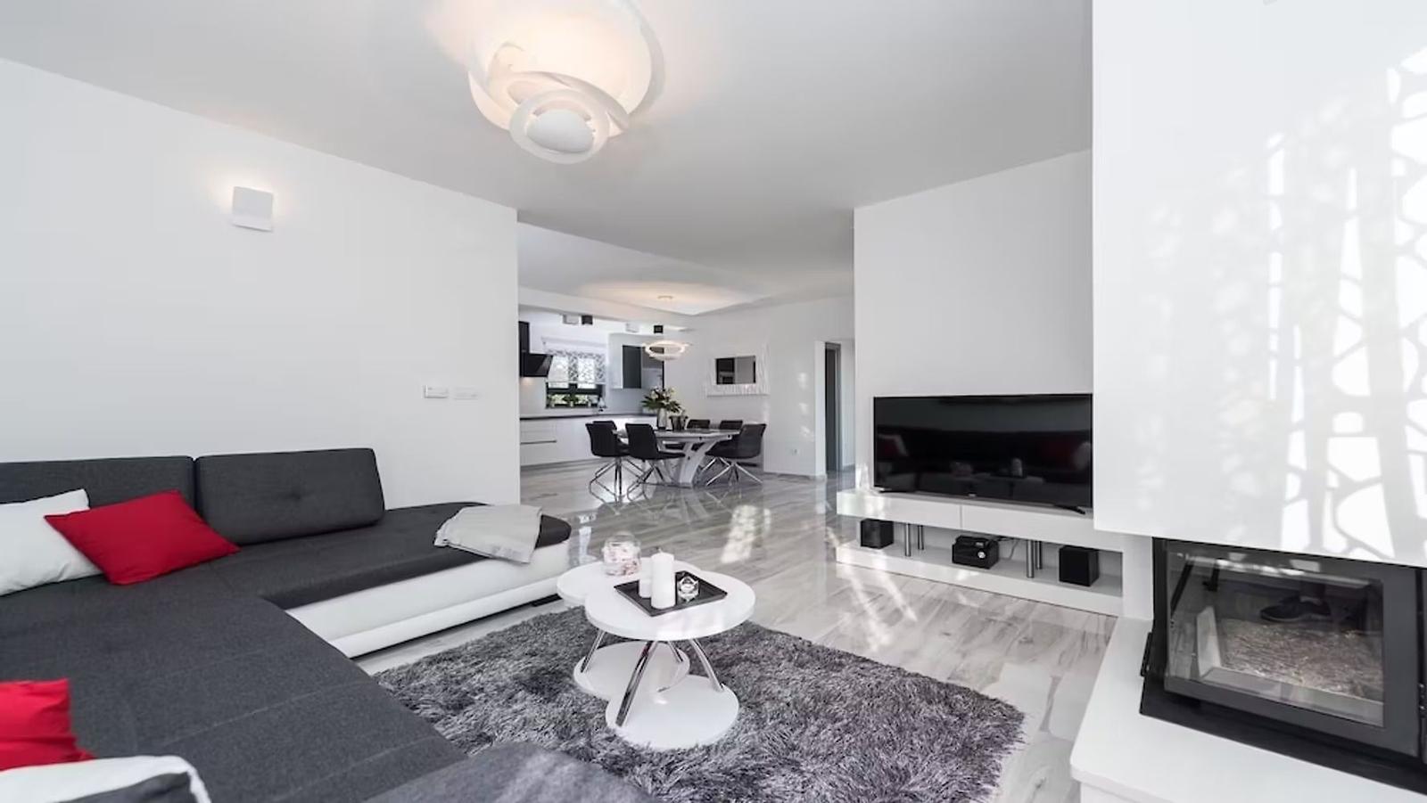 Living room with sofa, TV, and fireplace. Dining area in the background.