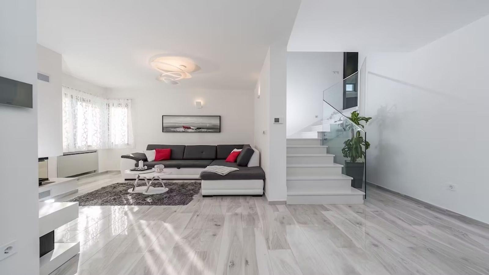 Living room with sofa, staircase, and ceiling light.