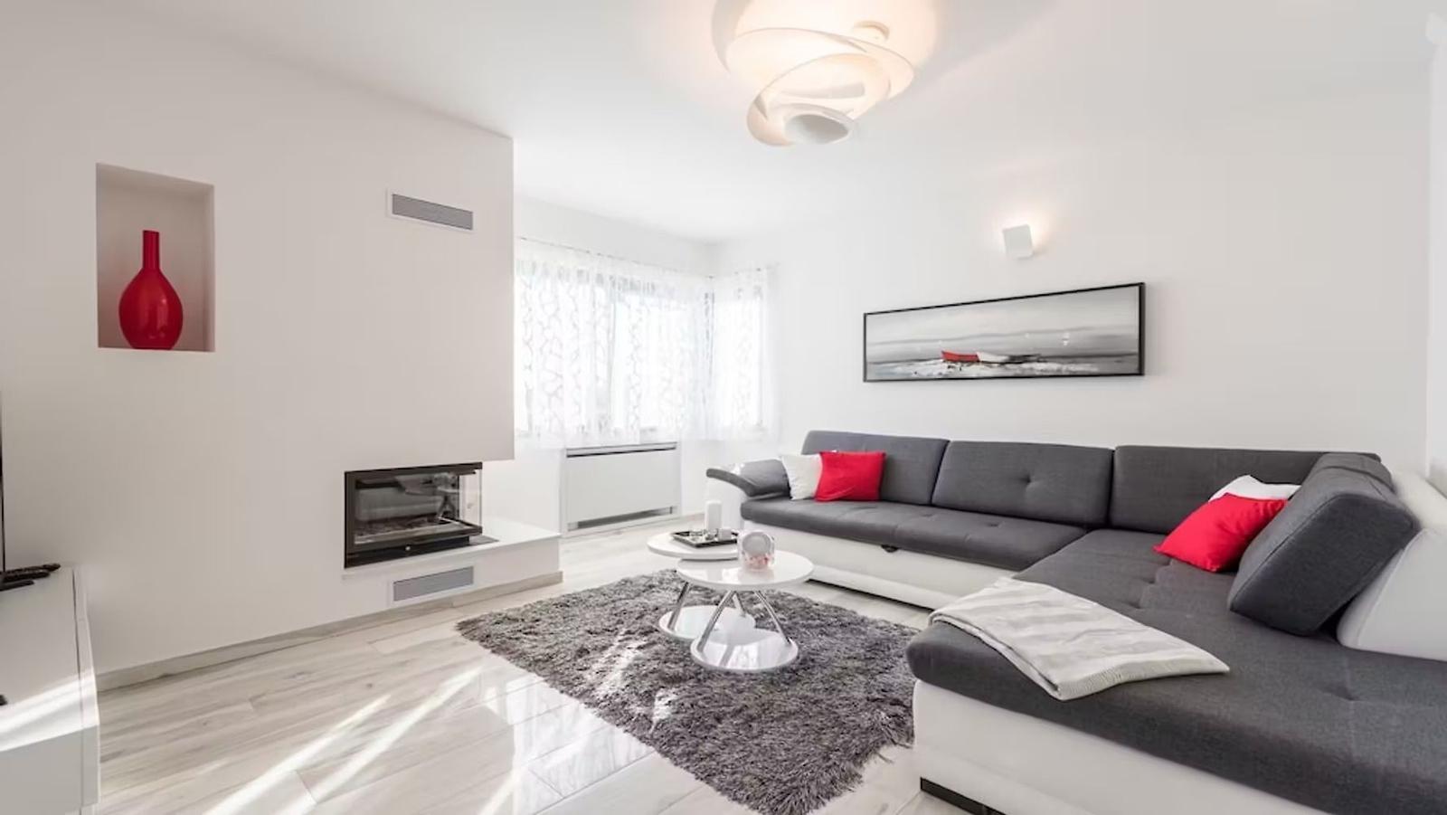 Living room with gray sofa, red cushions, and modern fireplace.