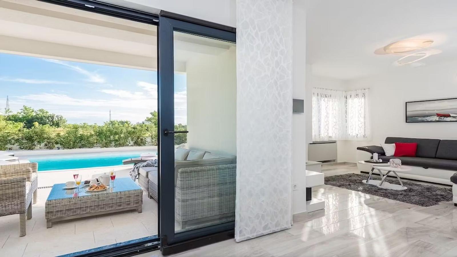 Terrace with pool and lounge area. Living room with sofa and rug.