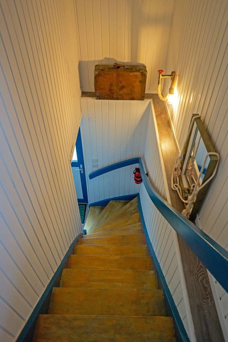 Holztreppe mit blauer Balustrade, Wandbeleuchtung und alter Kiste.