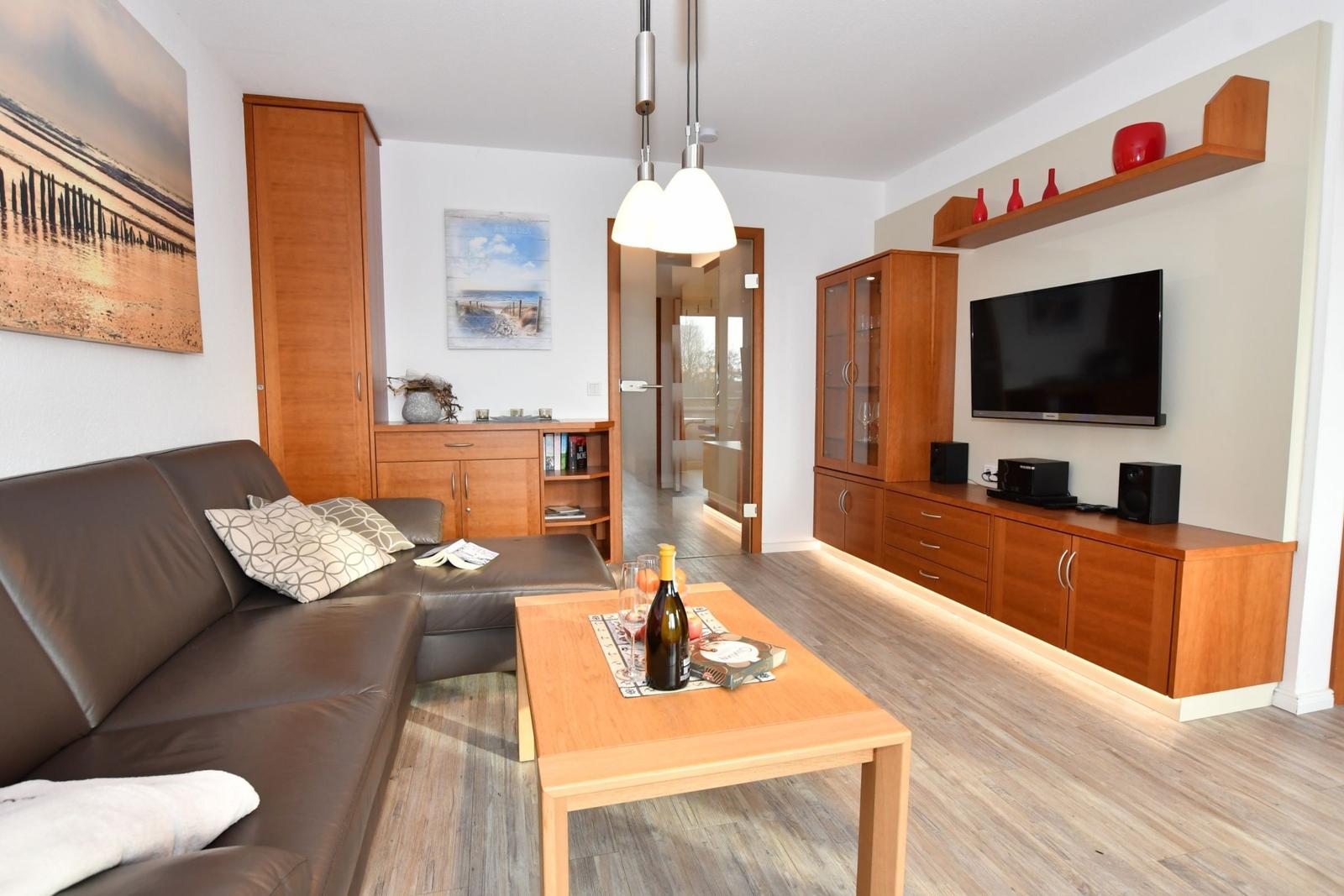 Wohnzimmer mit Sofa, Couchtisch und Fernseher an der Wand.