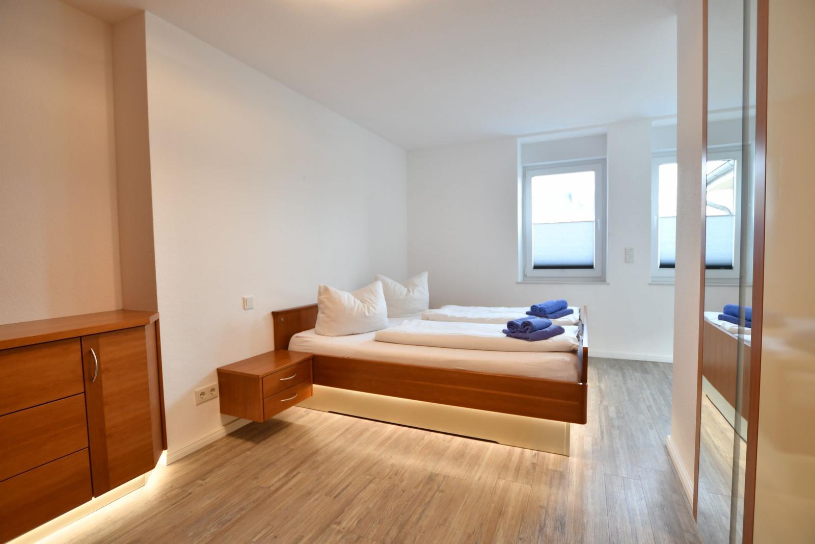 Schlafzimmer mit Doppelbett, Holzmöbel und Fenster.