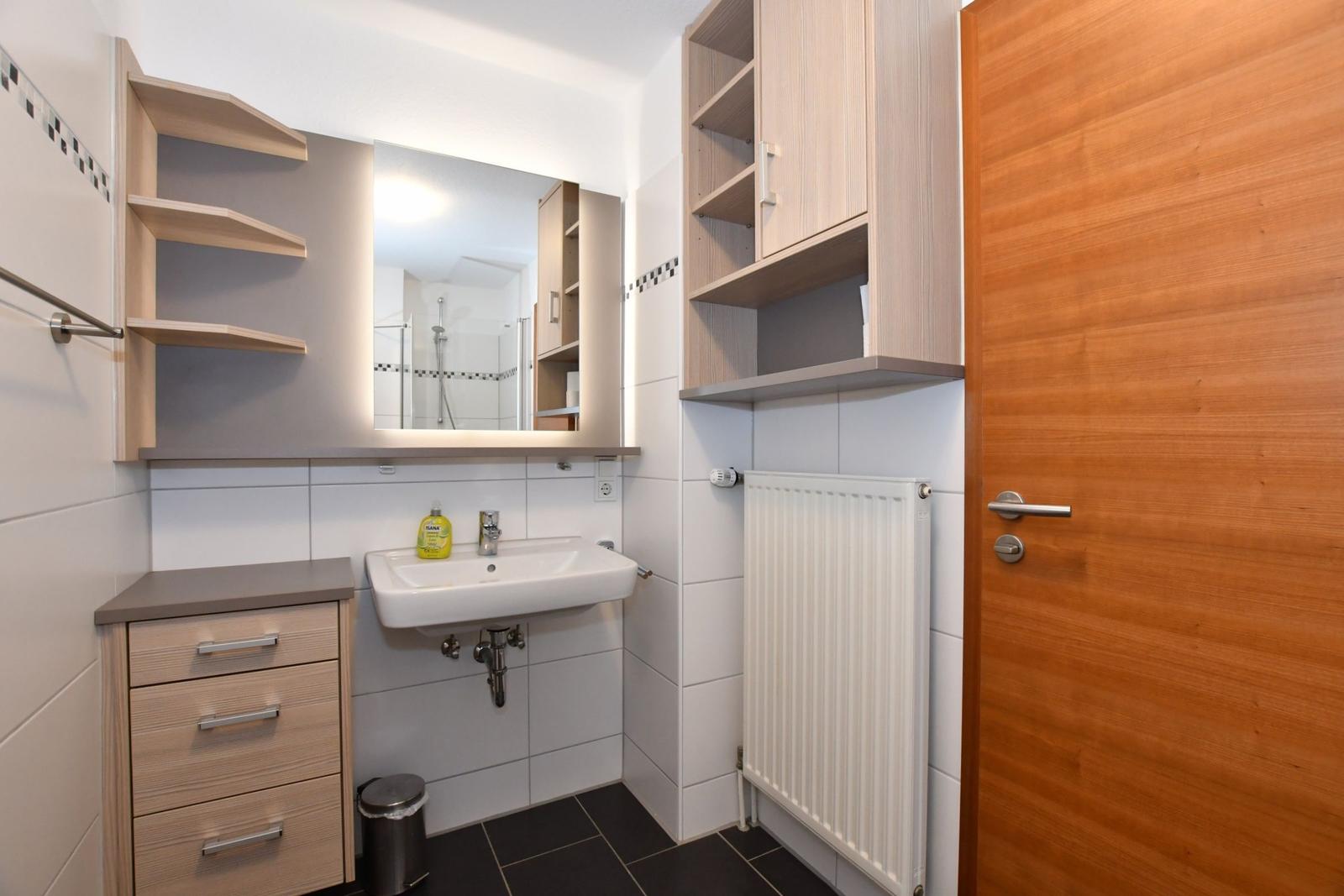 Badezimmer mit Waschbecken, Spiegel und Holzschränken.