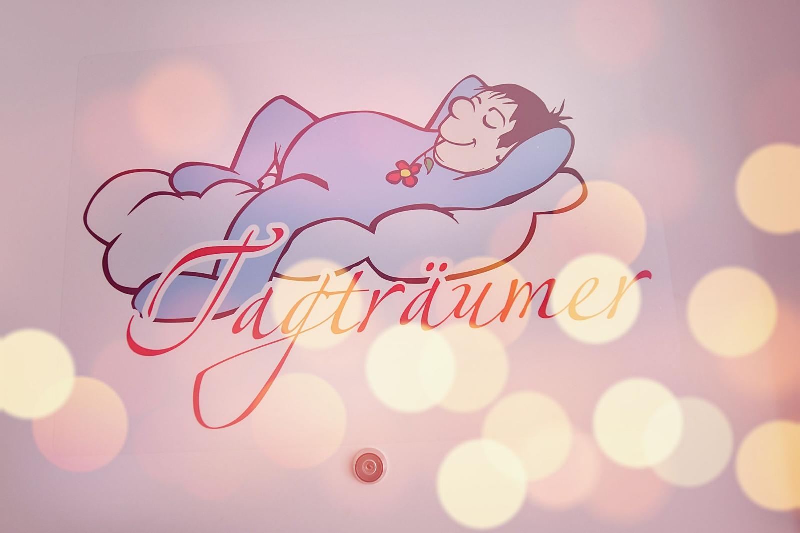 Ein Logo mit einem schlafenden Mann auf einer Wolke und dem Schriftzug Tagträumer.