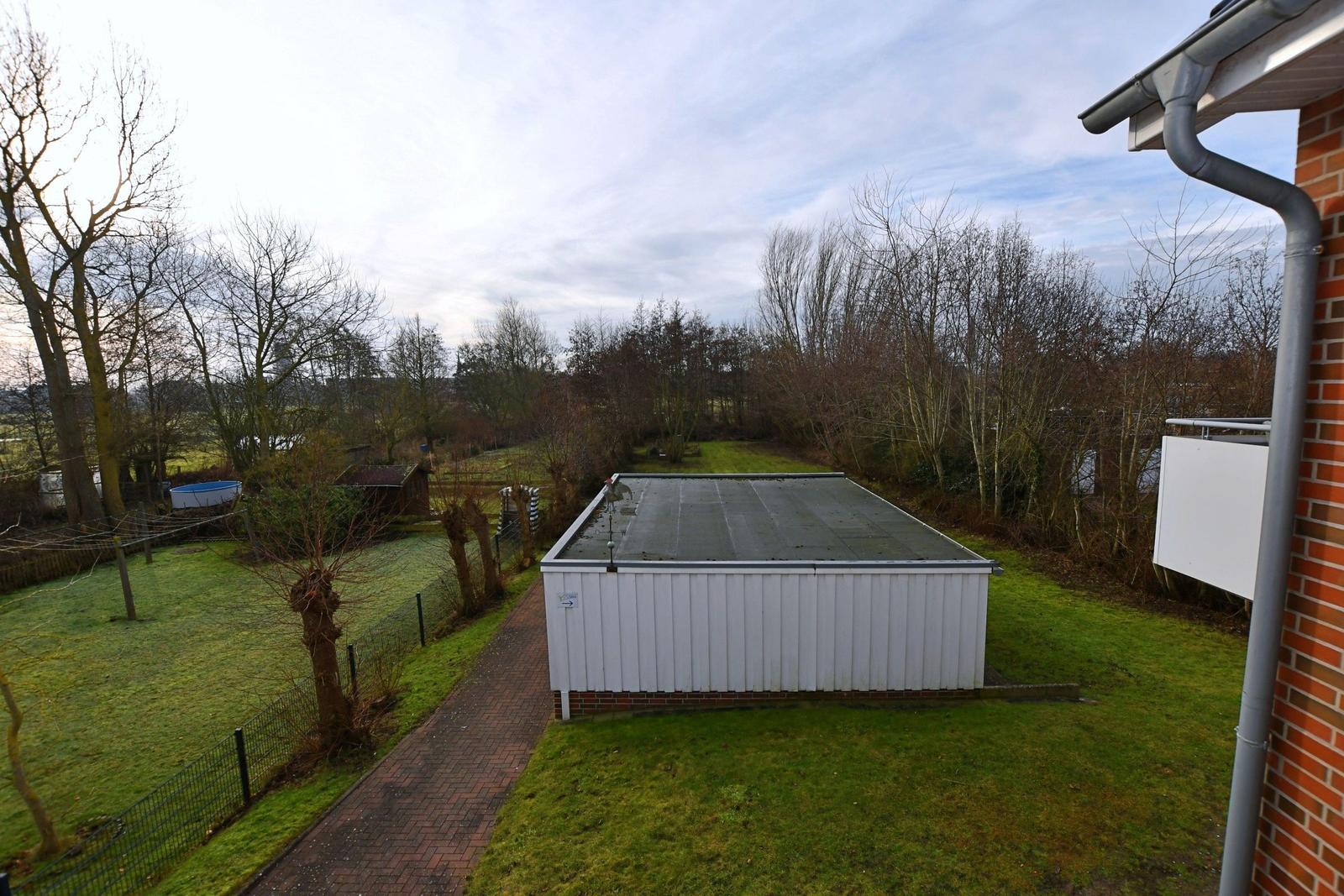 Hinterhof mit Poolhaus, Grillplatz und grünem Rasenbereich.