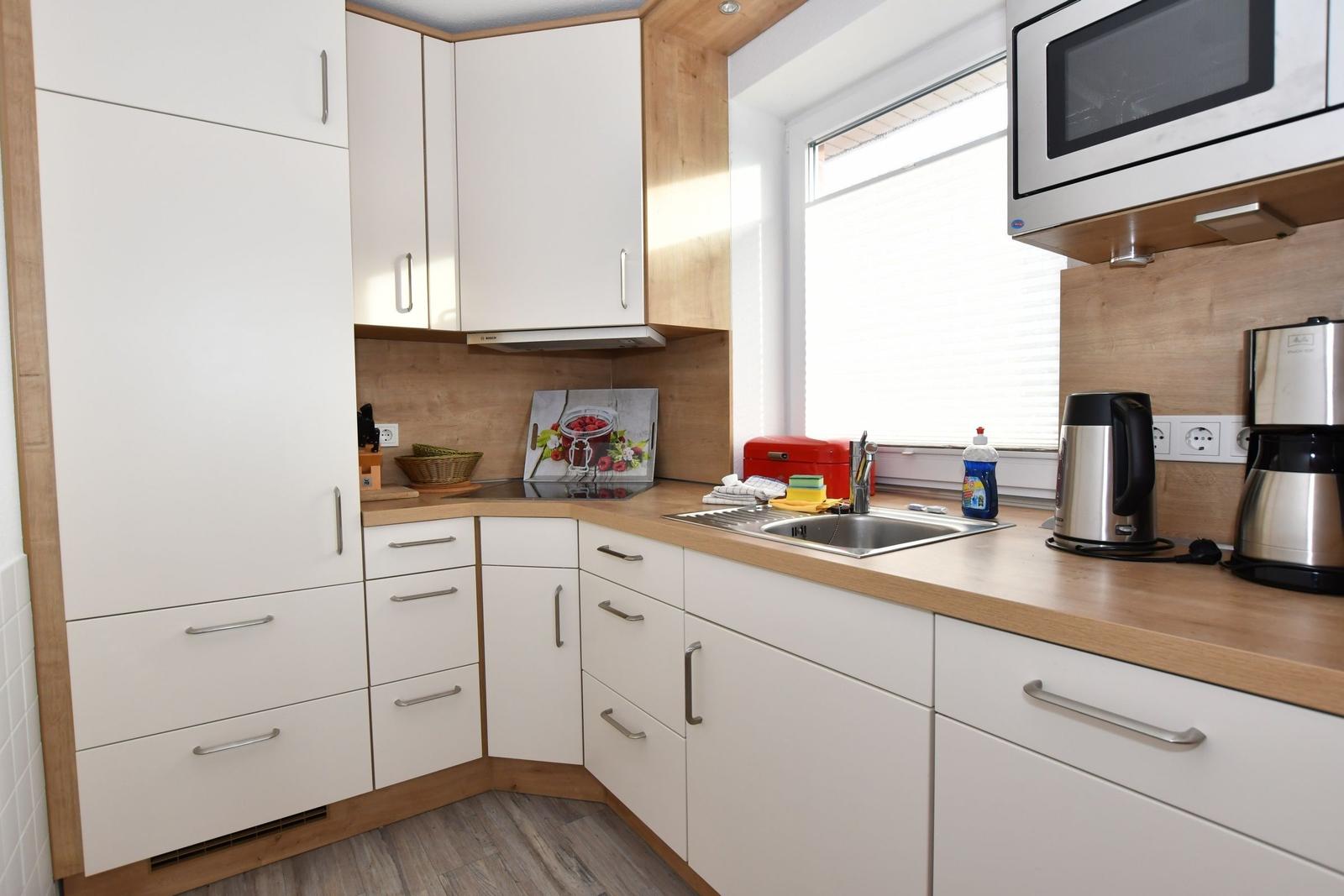 Küche mit weißen Schränken, Holzoberflächen und integriertem Mikrowellenherd.