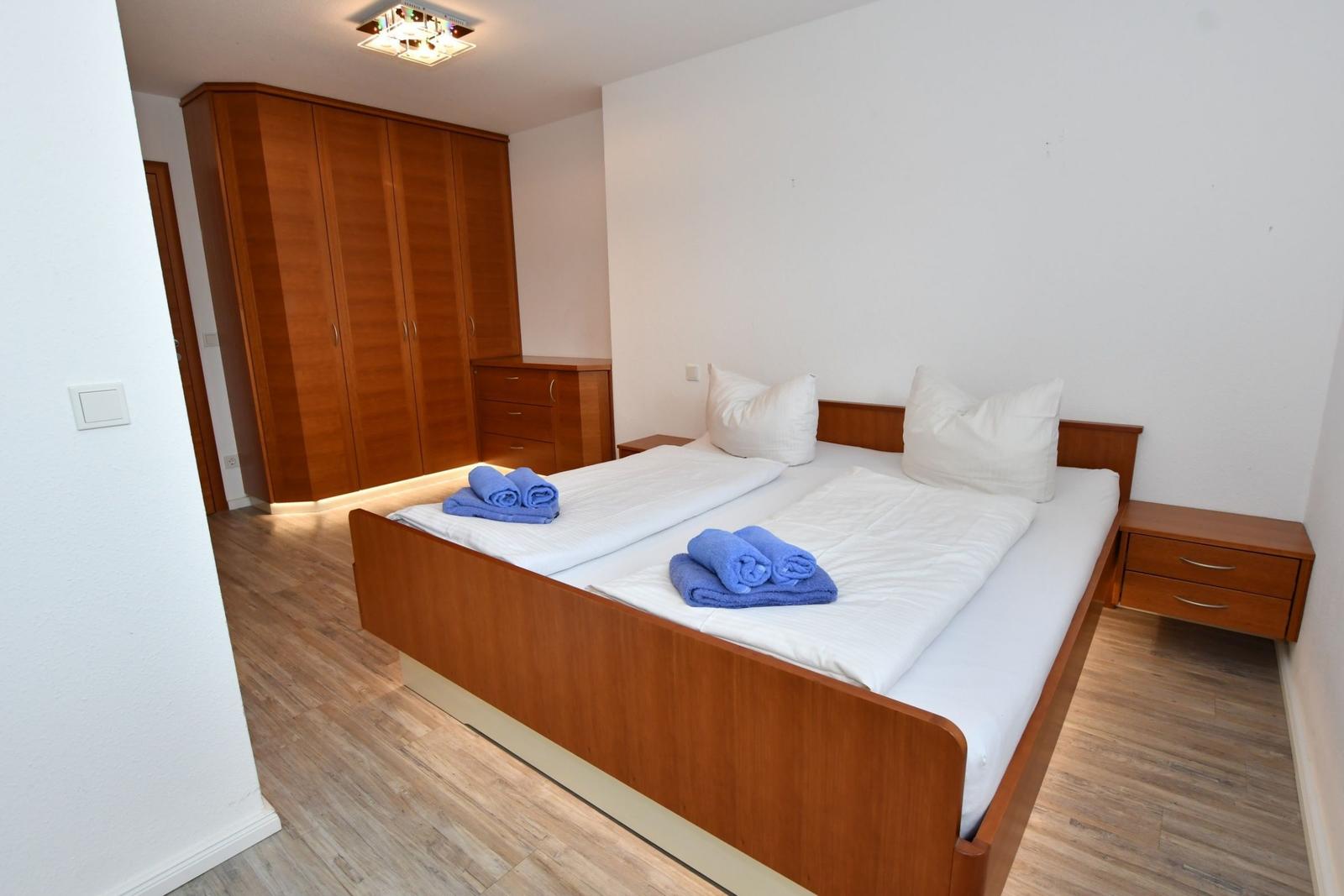 Schlafzimmer mit Doppelbett, Holzmöbel und Holzdielenboden.