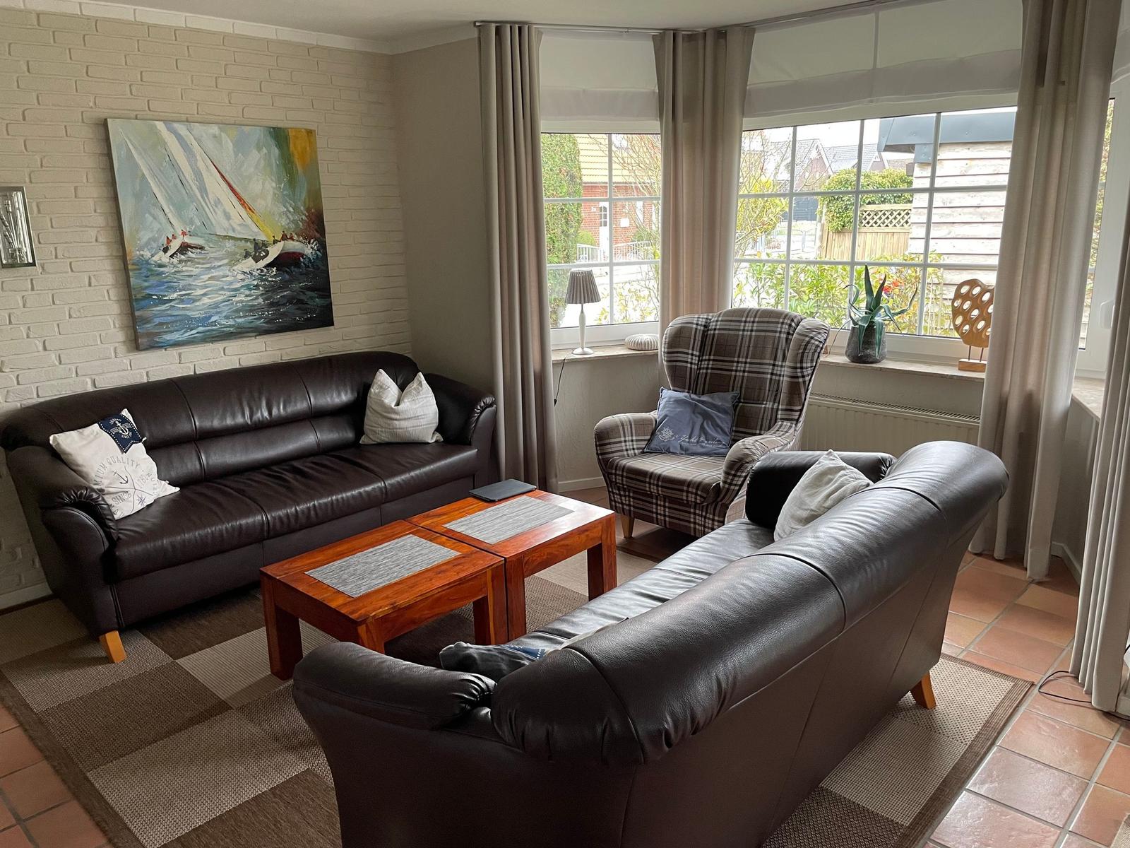 Wohnzimmer mit zwei Ledersofas, einem Holztisch und großem Fenster.