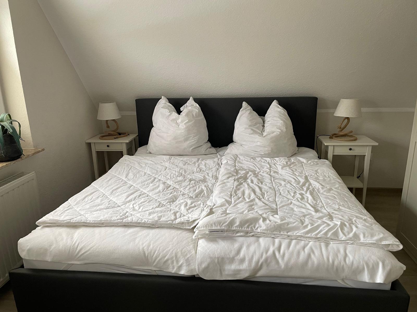 Schlafzimmer mit Doppelbett, zwei Nachttischen und Lampen unter schrägem Dach.