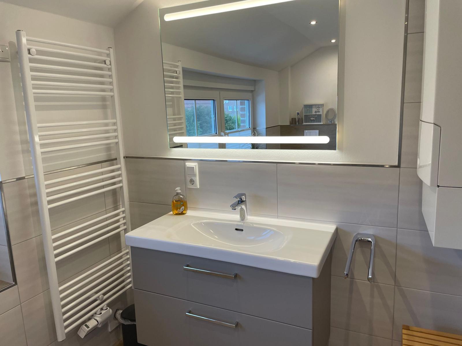 Badezimmer mit Waschbecken, Spiegel und Heizkörper
