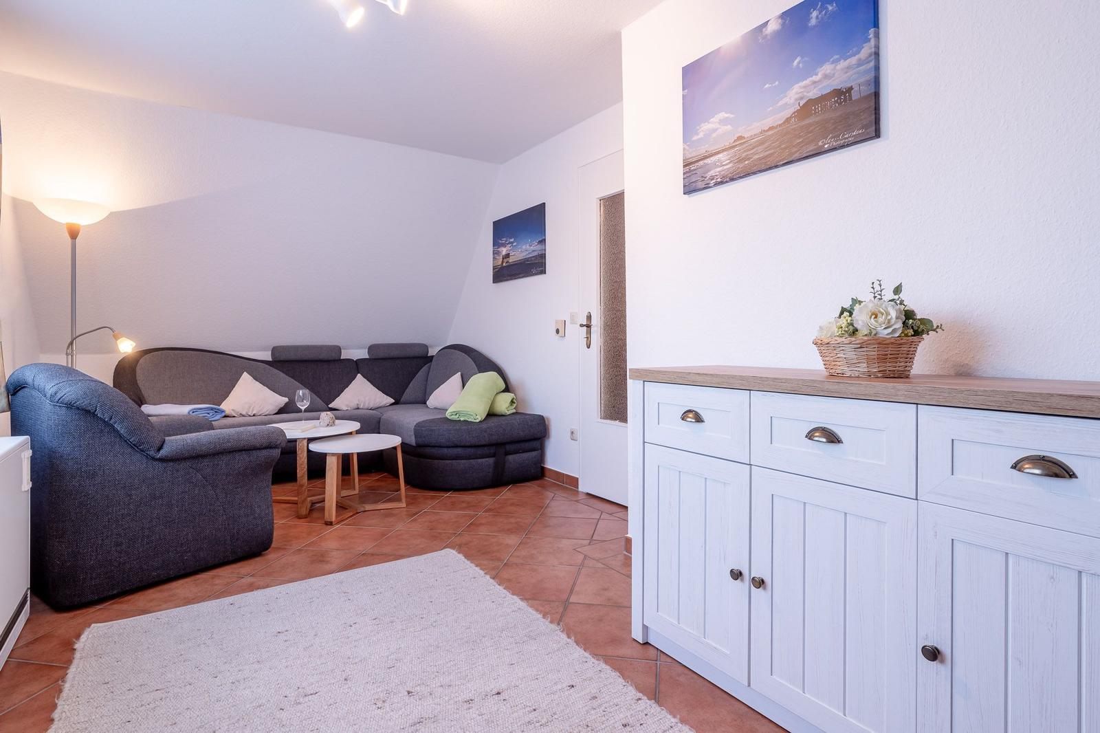 Wohnzimmer mit Sofa, Sessel und Sideboard. Wandbild und Teppich sind sichtbar.