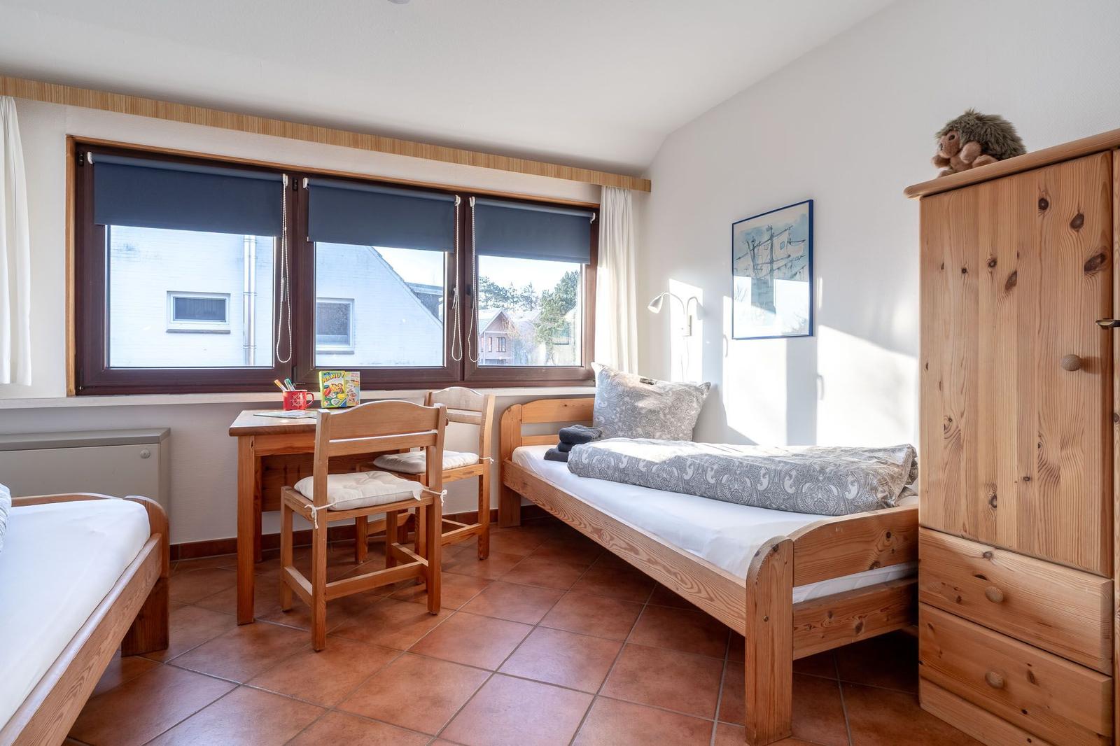 Zimmer mit zwei Betten, Schreibtisch, Kleiderschrank und Fenster mit Blick nach draußen.