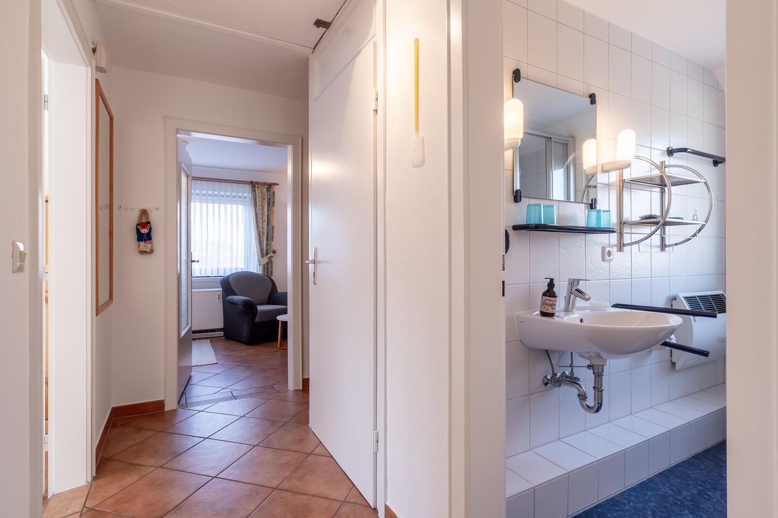 Flur mit Bad und Blick in Wohnbereich mit Sessel.