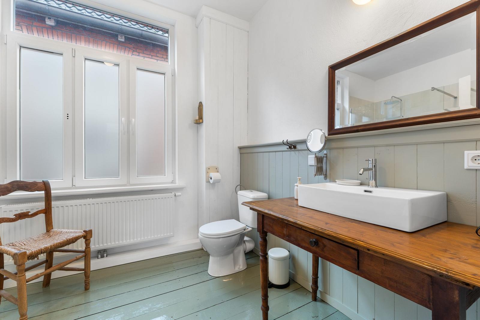 Badezimmer mit Waschtisch auf Holzbank, Toilette und Fenster mit Milchglas.