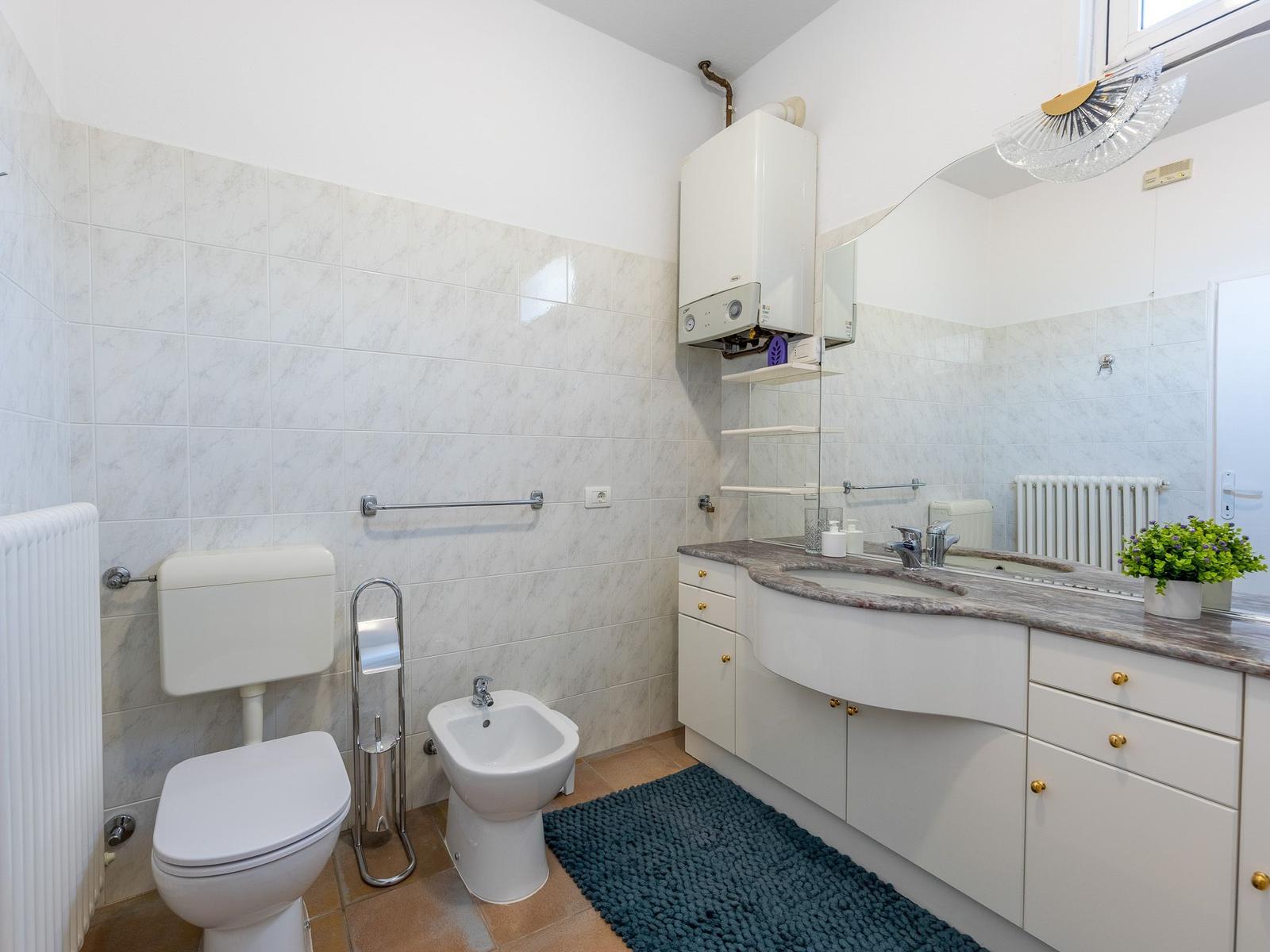 Badezimmer mit Toilette, Bidet, Waschbecken und Heizkörper