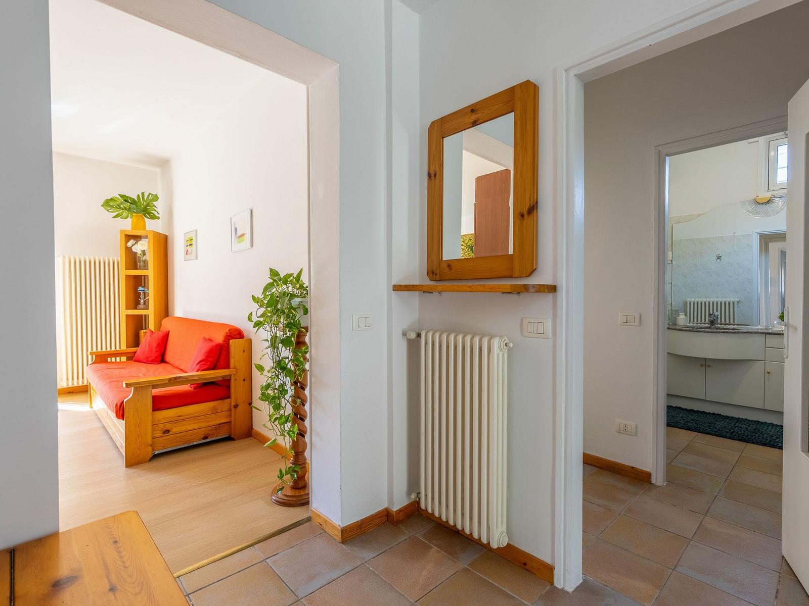 Eingangsbereich mit Spiegel, Heizkörper und Blick in Wohn- und Badezimmer.