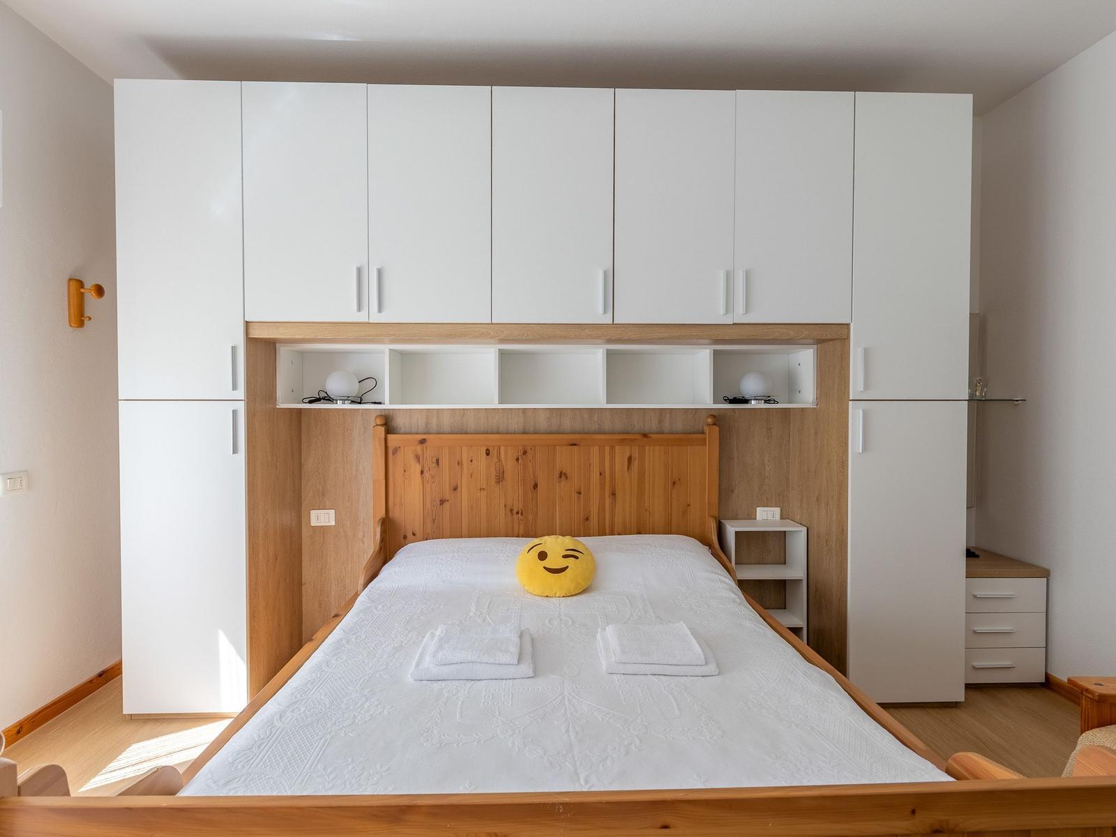 Schlafzimmer mit Bett, weißen Schränken und Holzgestell.