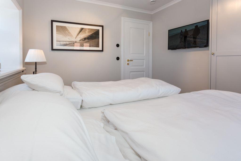 Schlafzimmer mit Bett, Wandbild, TV und Lampen.