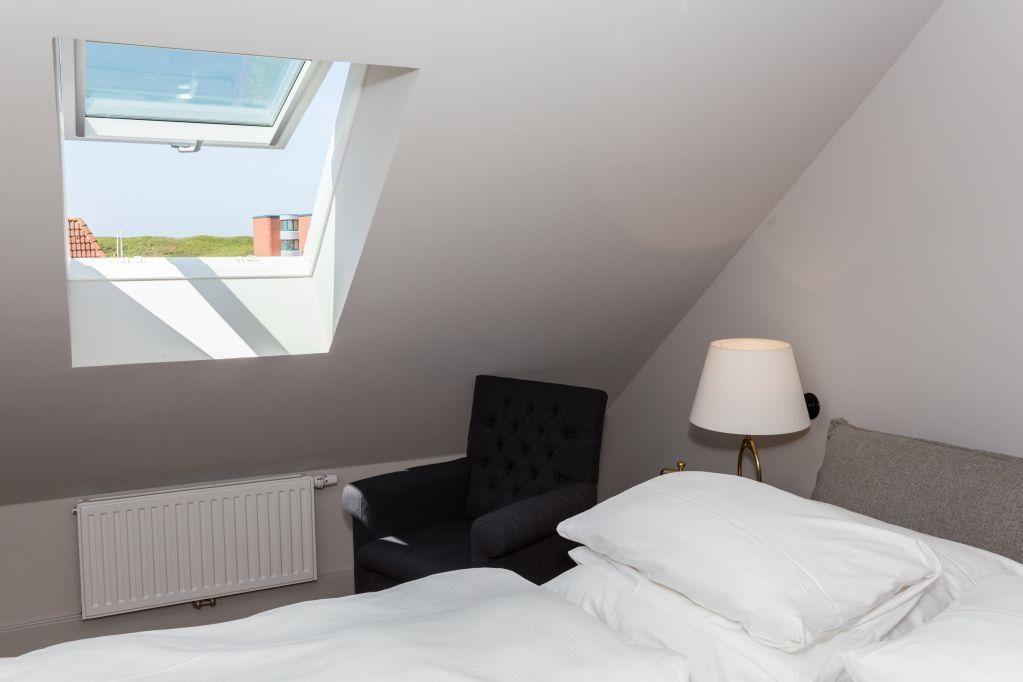 Schlafzimmer mit Dachschräge, Fenster und Bett