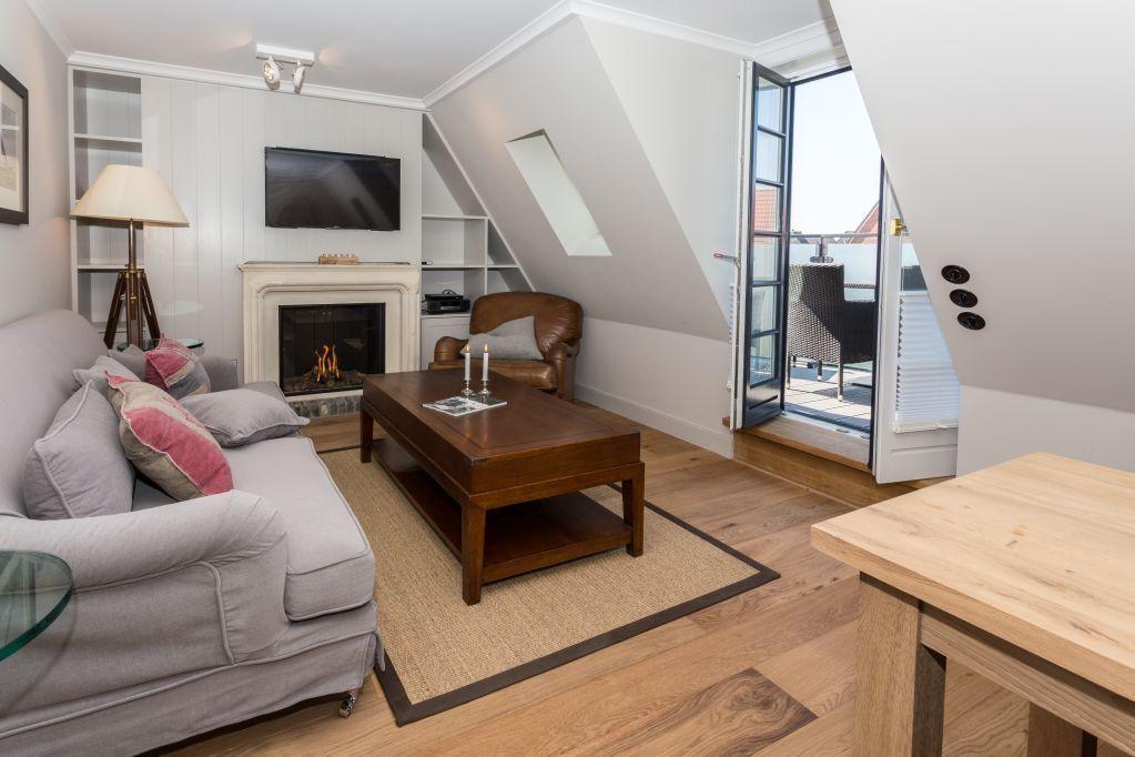 Wohnzimmer mit Kamin, Sofa, Couchtisch und Terrassentür.