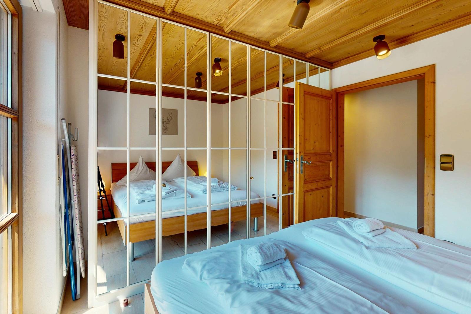 Schlafzimmer mit Spiegelschrank, Holzbett und Holzdecke. Handtuch auf dem Bett.