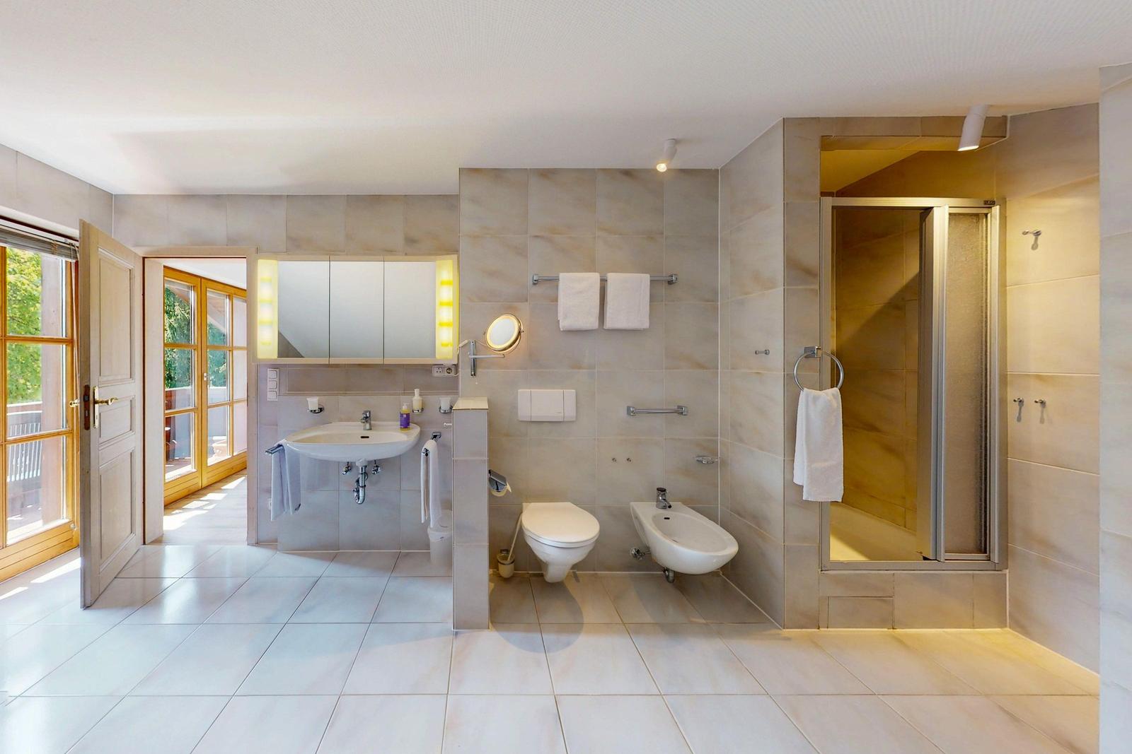 Bad mit Dusche, Waschbecken, WC und Bidet. Tür führt auf Balkon.