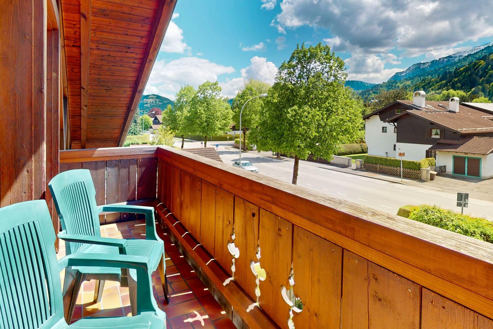 Terrasse mit zwei grünen Stühlen und Blick auf Straße und Berge.