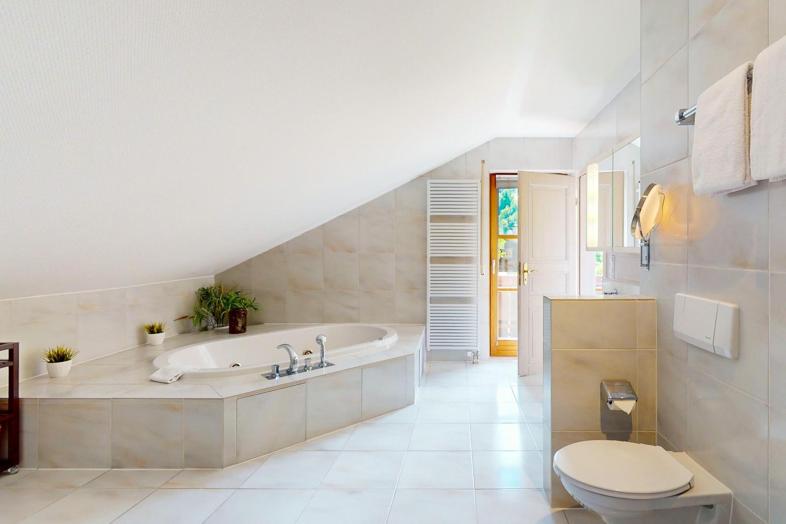 Dusche, Badewanne und Toilette in einem hellen Badezimmer mit Dachschrägen.