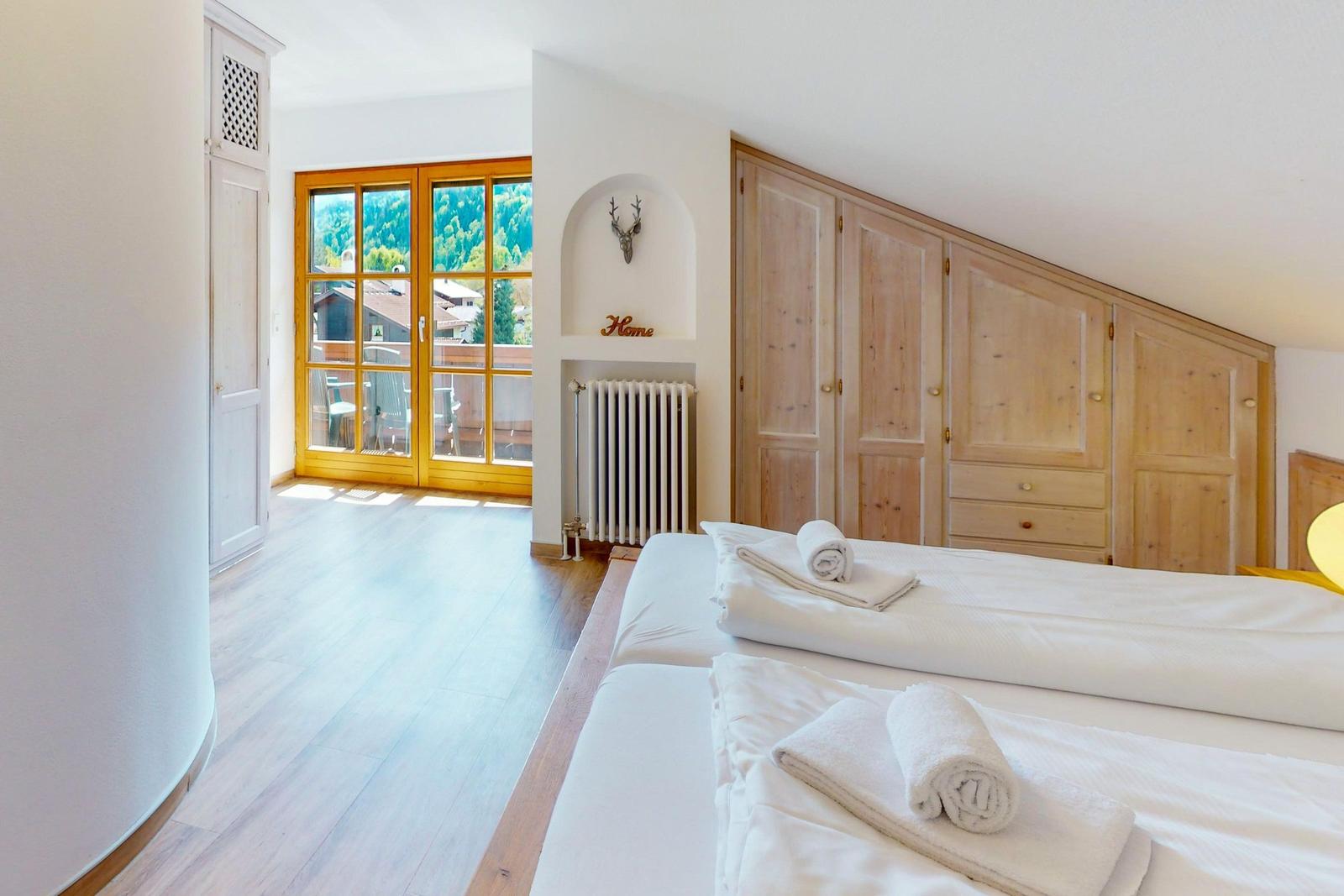Zimmer mit zwei Betten, Holzmöbeln und Blick auf die Berge.