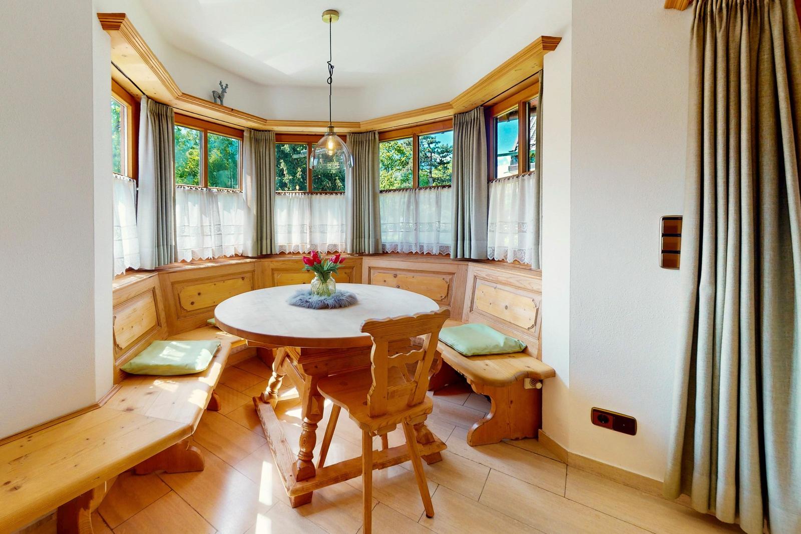 Rundtisch mit Holzbank und Fensterblick in rustikalem Stil.