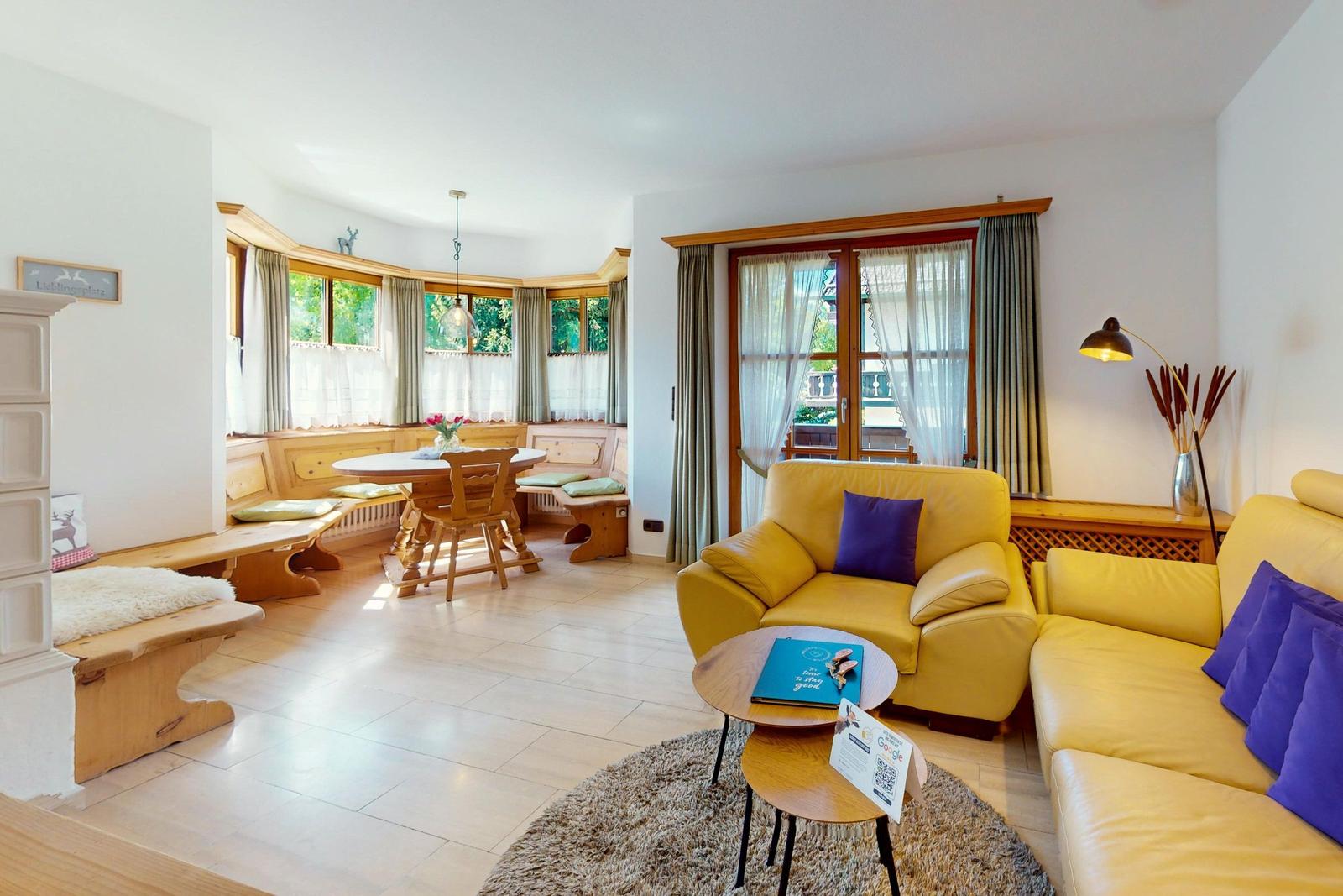 Wohn- und Essbereich mit gelben Ledersofas, Holzmöbel und großen Fenstern.