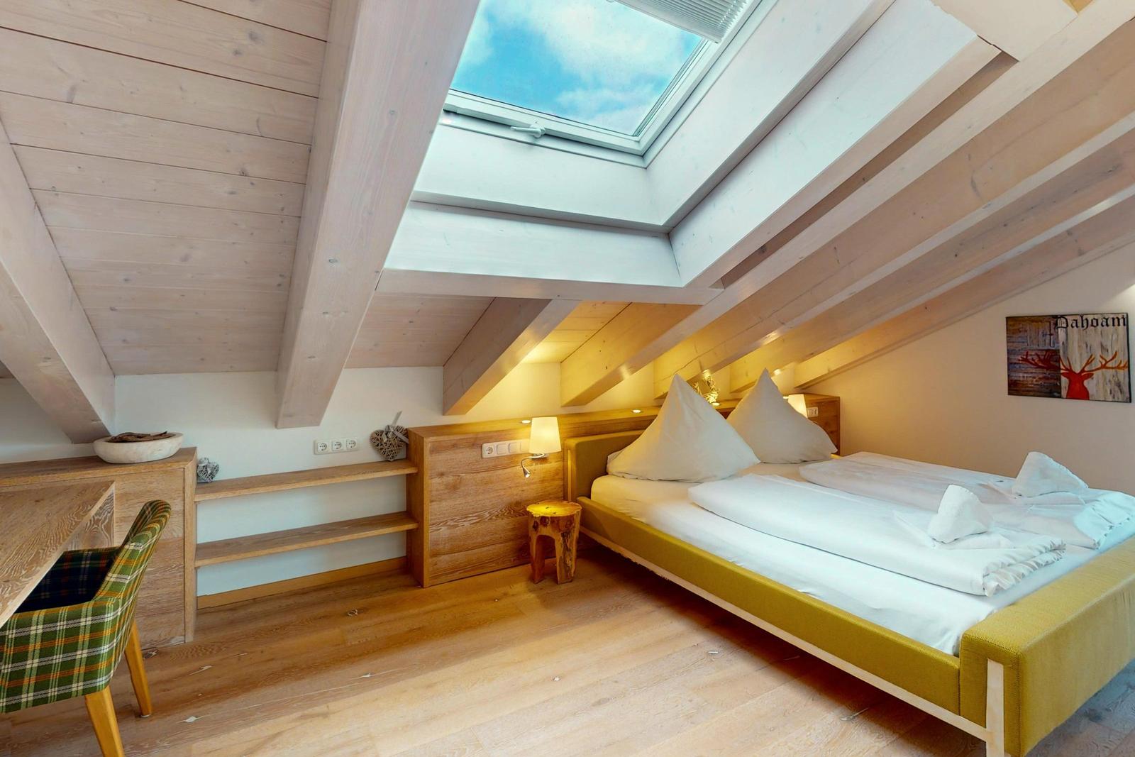 Schlafzimmer mit Dachschrägen, Dachfenster und Holzmöbeln.