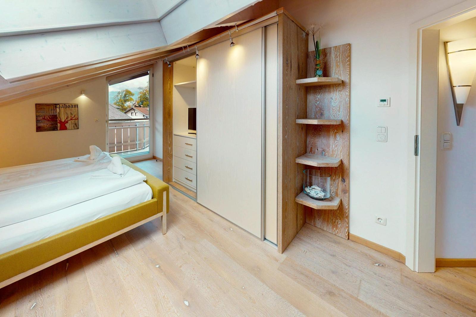 Schlafzimmer mit Bett, Kleiderschrank und Balkonansicht.