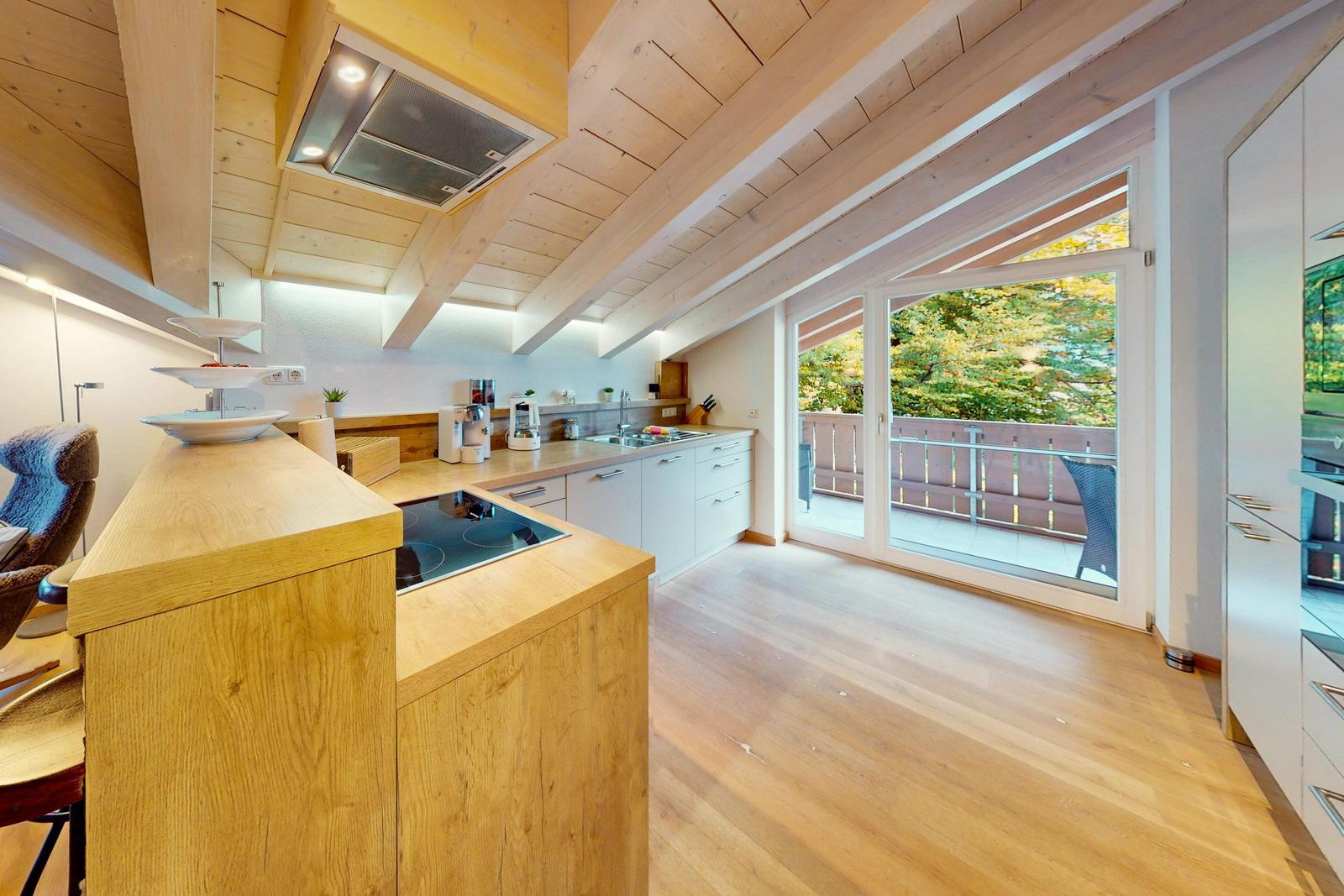 Küche mit Holzdecke und Balkonanschluss. Moderne Einrichtung und hellen Holzboden.
