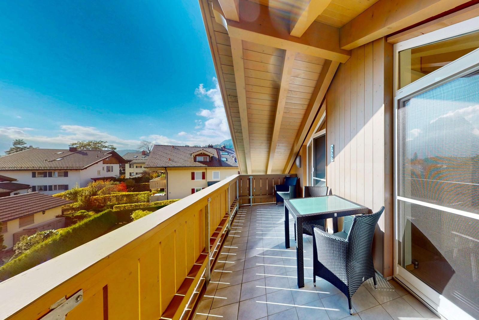 Terrasse mit Tisch und Stühlen, Holzverkleidung und Blick auf Wohnhäuser.