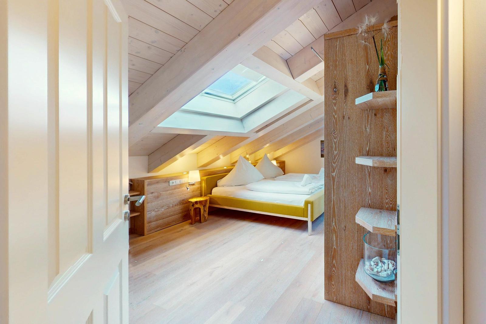 Schlafzimmer mit Dachschrägen, Dachfenster und gelbem Bett