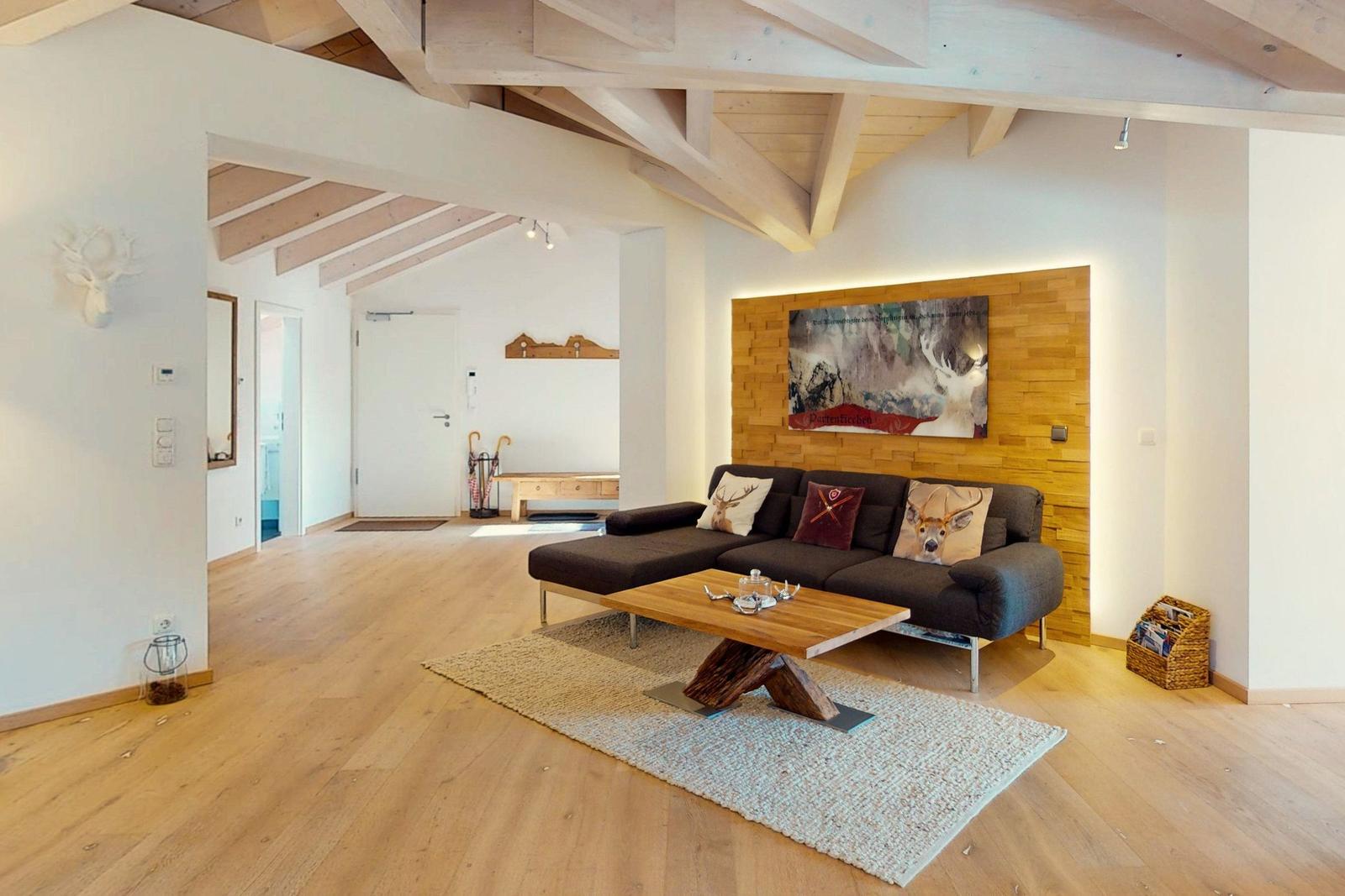 Wohnzimmer mit Holzboden, Sofa und Tisch. Deckenbalken und Wandbild sichtbar.